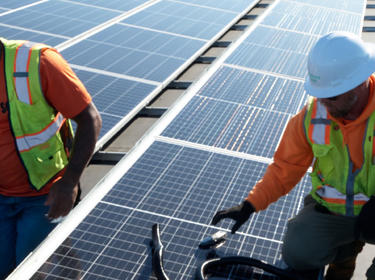 Two men working on a roof installing solar panels