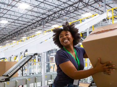 Smiling woman in bright LED lights lit warehouse