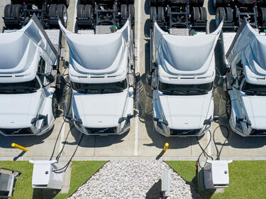 An overhead view of four electric fleet trucks charging at an EV charging station
