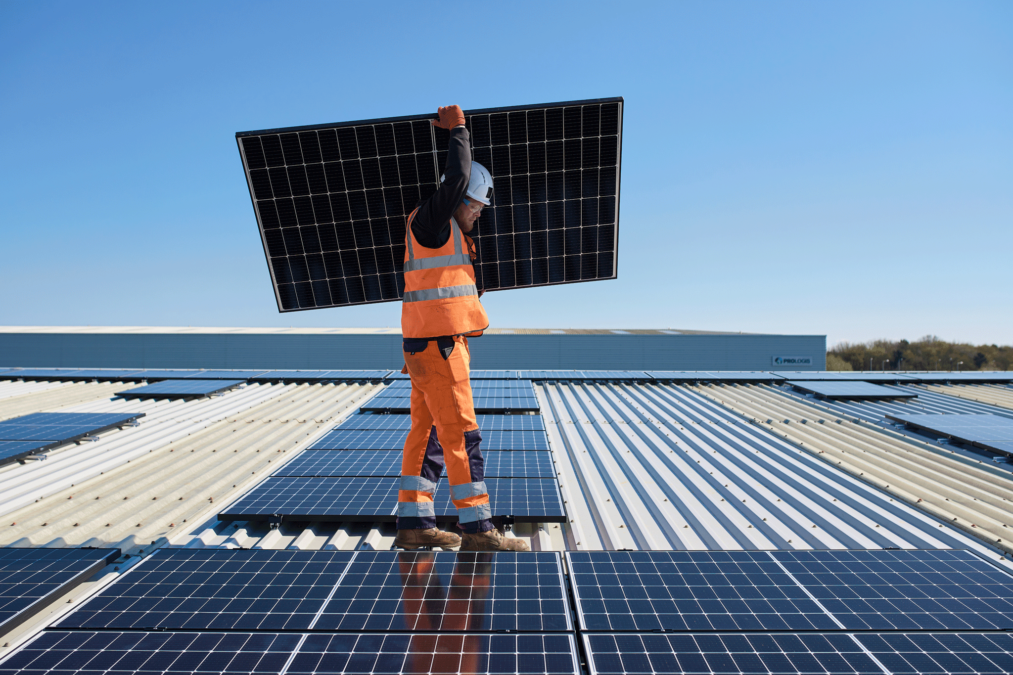 Person trägt ein Solarmodul auf einem Dach Person trägt ein Solarmodul auf einem Dach